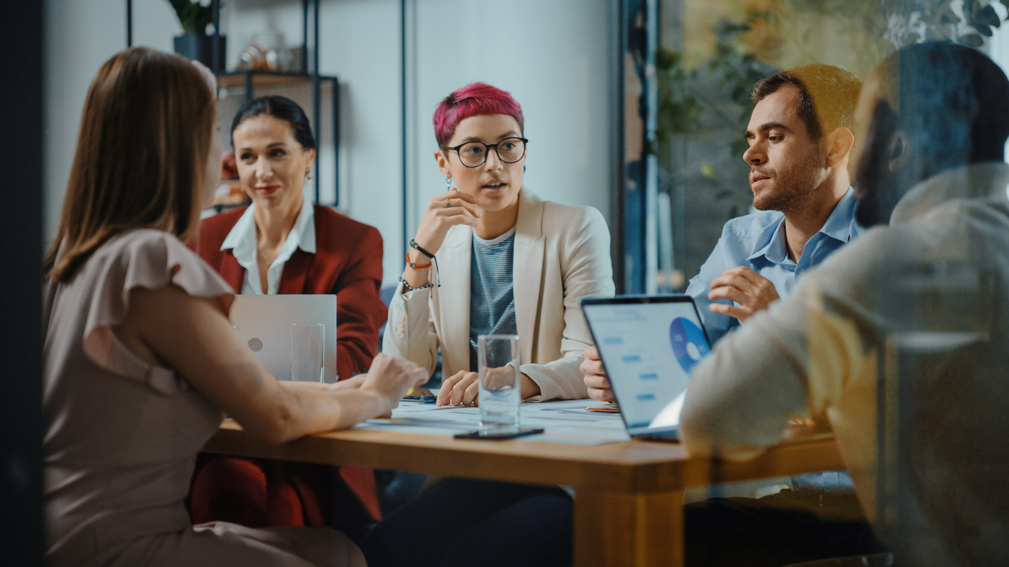 A person sits in the middle of colleagues working at a table during a meeting.