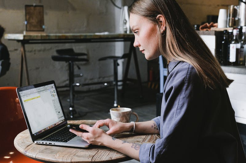 A woman works in a coffee shop on her laptop
