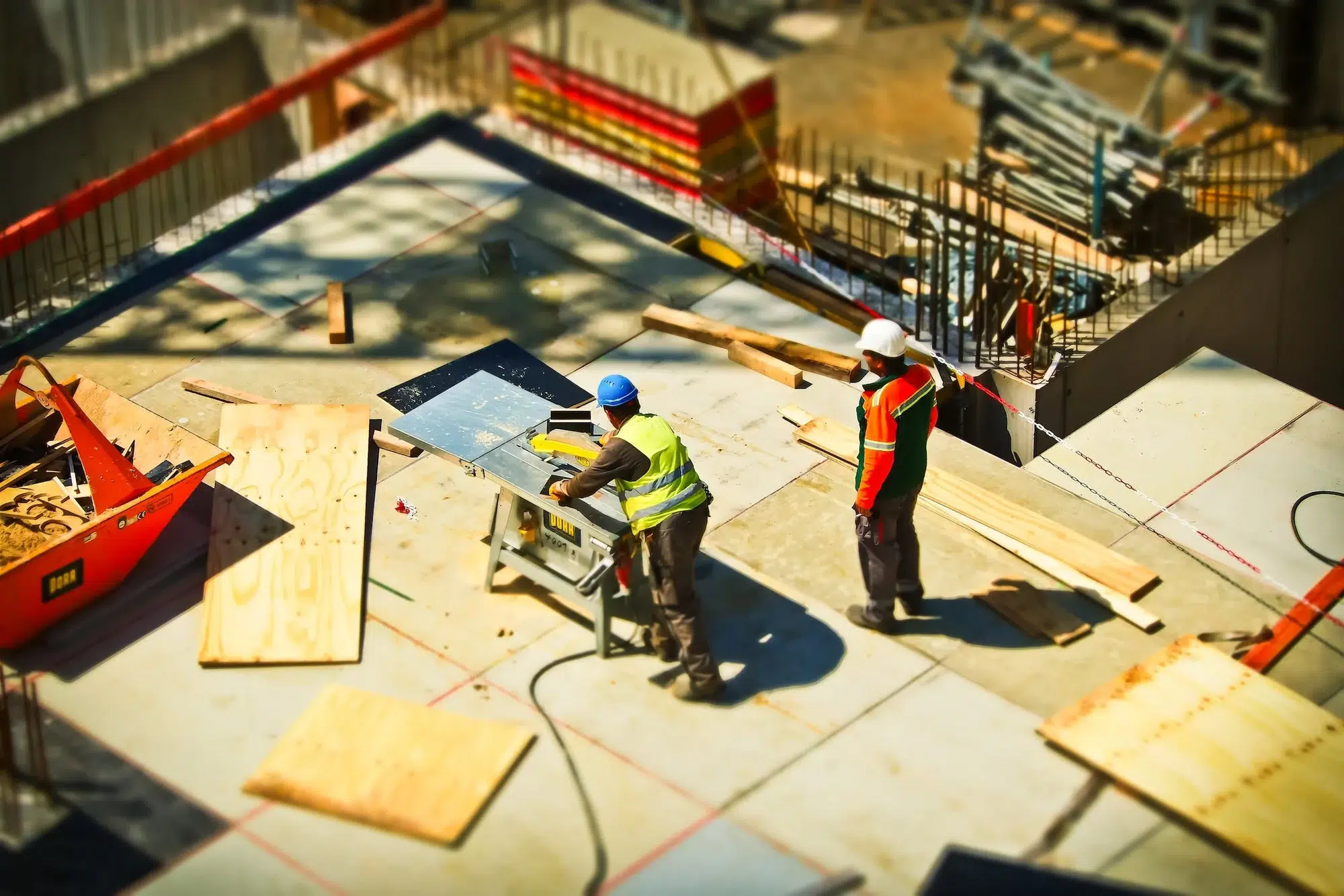 An image from above; two men work on the roof of a construction site.