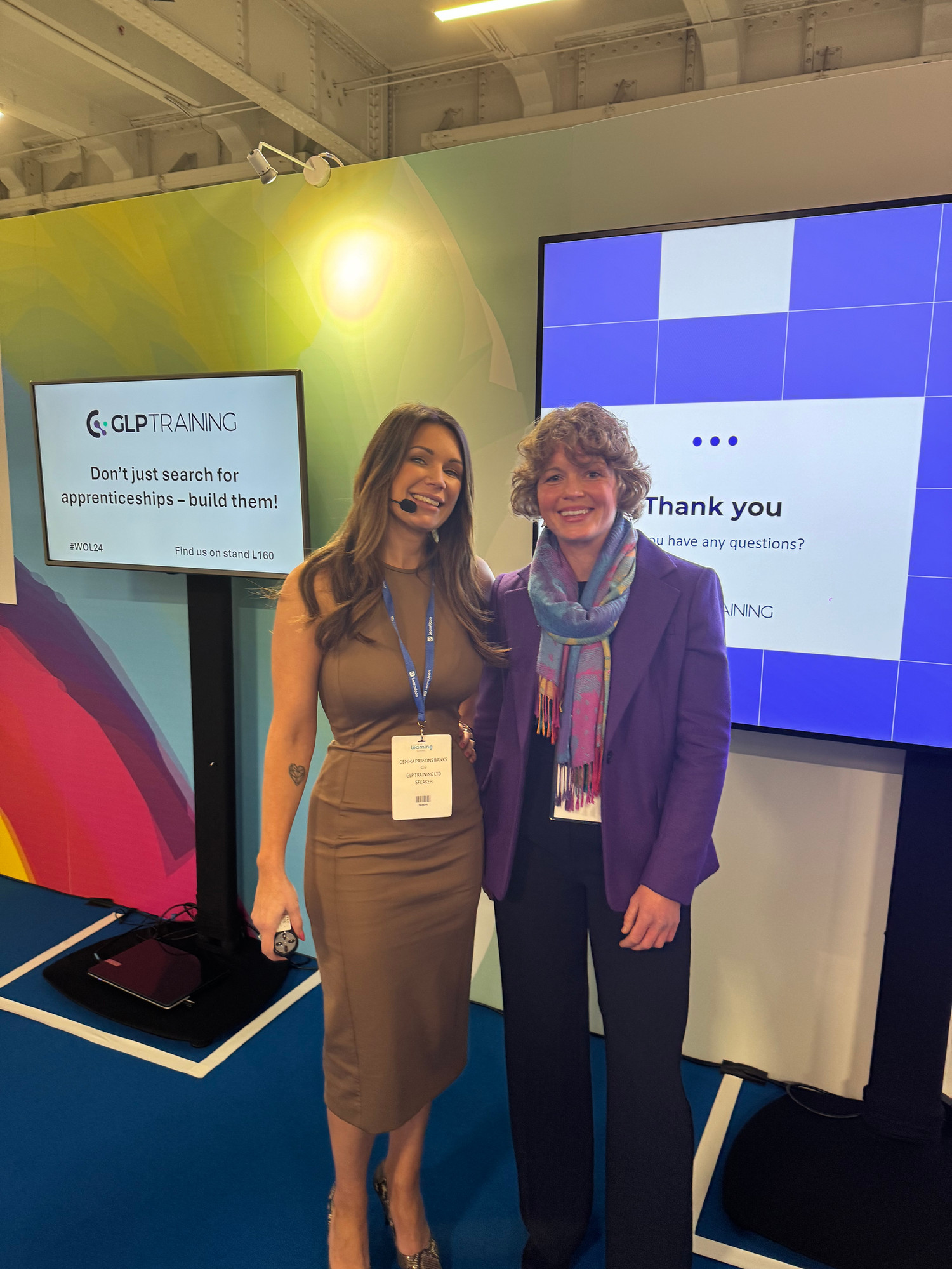 Two women in formal wear pose for the camera at a GLP Training event