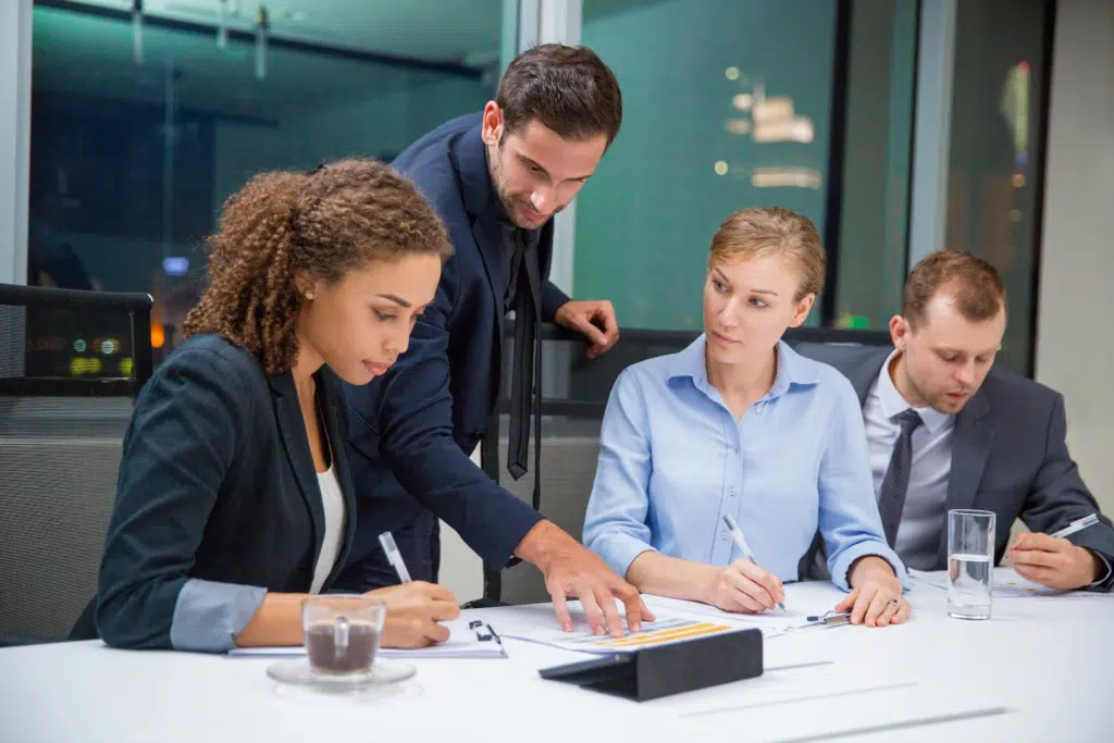 4 members of a leadership team work in a corporate office together in business wear.