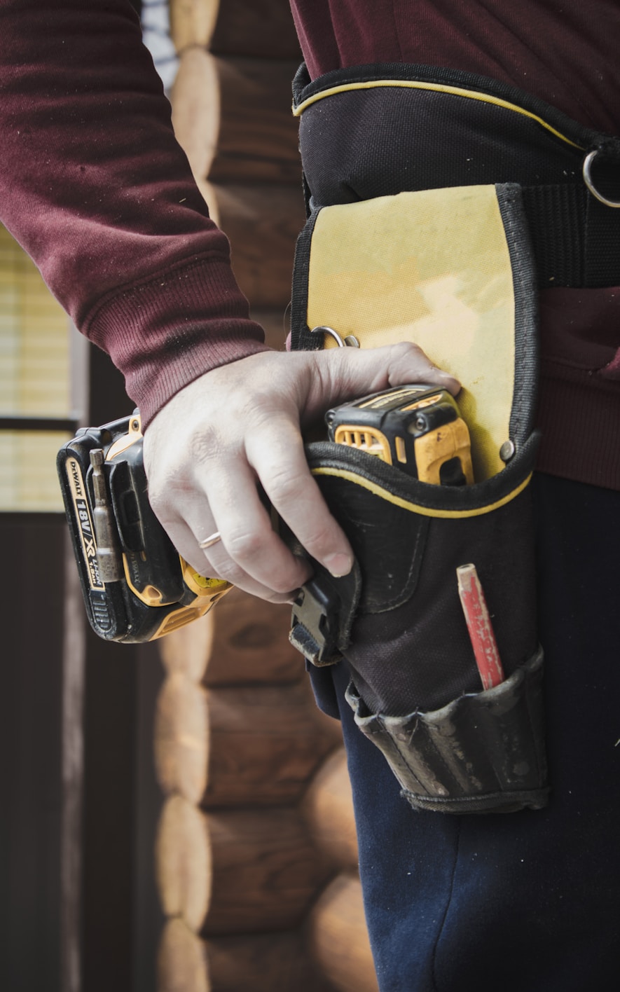 A hand rests on a tool in a tool belt