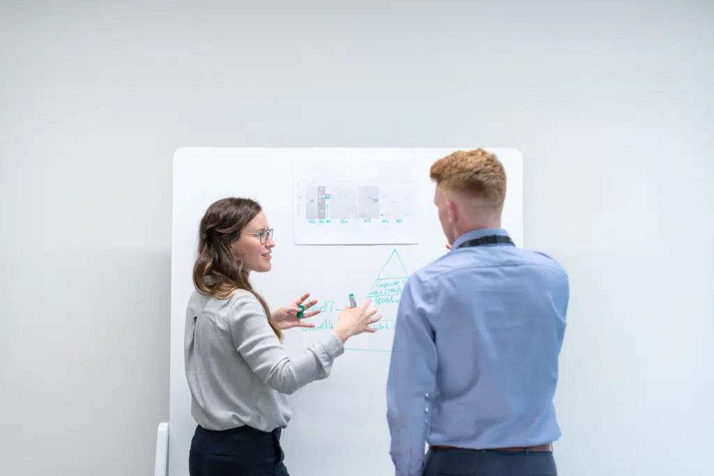 Two people, a man and a woman, collaborate together with graphs and a pyramid chart.