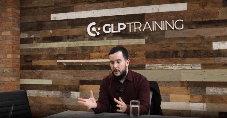 Peter Hutchinson sits under a GLP Training logo talking at a table.